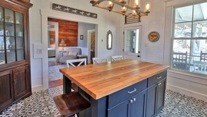 Una cocina con una isla de madera, armarios oscuros y una araña.