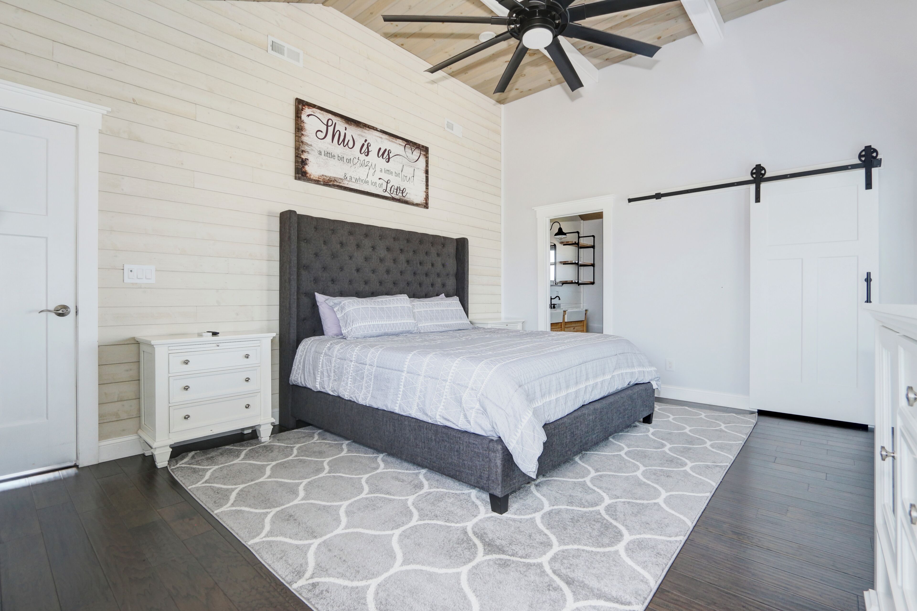 A bedroom with a bed, nightstand, dresser, and a ceiling fan.