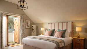 Un dormitorio con una cama grande, dos mesitas de noche, una puerta de madera y vistas al exterior.