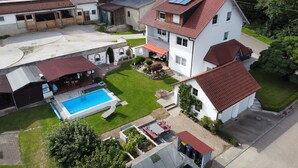 An aerial view of a residential area with a swimming pool, a covered patio, and a well-maintained lawn.