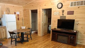 Ein Holzinterieur mit Esstisch, Stühlen, Fernseher und Kühlschrank.