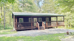 Eine Hütte mit Veranda, mehreren Fenstern und einem Schotterweg.