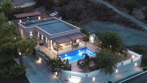 A modern house with a swimming pool, outdoor seating, and a well-lit patio area. - Amelia Residence (Zakynthos)