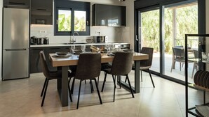 A modern kitchen with a dining area, featuring a large window, built-in appliances, and a casual seating arrangement. - Amelia Residence (Zakynthos)