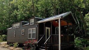 Une cabane dotée d’une véranda, d’un petit escalier et d’une allée gravillonnée.