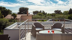 A rooftop terrace with wicker furniture, a table with drinks, and a view of a body of water and trees. - Nina in Peroj  - Haus für 6 Personen (Fazana)