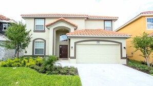 A two-story house with a beige exterior, a brown door, and a garage. - Solterra Resort 6 Bed Pool Spa Game Room 6 Bedroom Home by Redawning (Davenport)