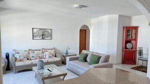 A living room with a sofa, a coffee table, a red cabinet, and a framed artwork on the wall.