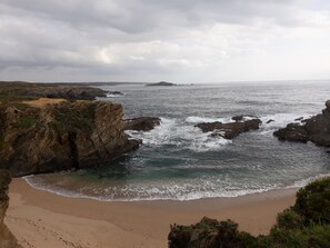 A coastal landscape with rocky cliffs and a sandy beach. - Apartamento Casal Nobre (Vila Nova de Milfontes)