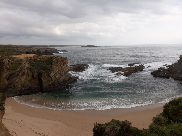 A coastal landscape with rocky cliffs and a sandy beach.