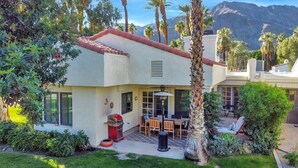 A house with a patio, a barbecue grill, and a view of mountains.