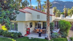 A house with a patio, a barbecue grill, and a view of mountains.