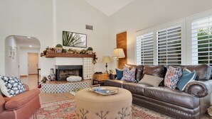 A living room with a fireplace, leather sofa, ottoman, and patterned rug.