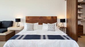 Una camera d'albergo con un letto grande, due comodini, un divano e un armadio.