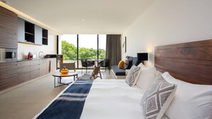 Una camera d'albergo moderna con un letto grande, un'area da pranzo e una cucina.