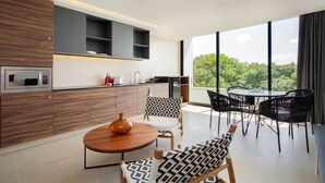 Una cucina moderna con elettrodomestici integrati, un'area pranzo con tavolo e sedie rotonde, e un'ampia finestra con vista sul verde.