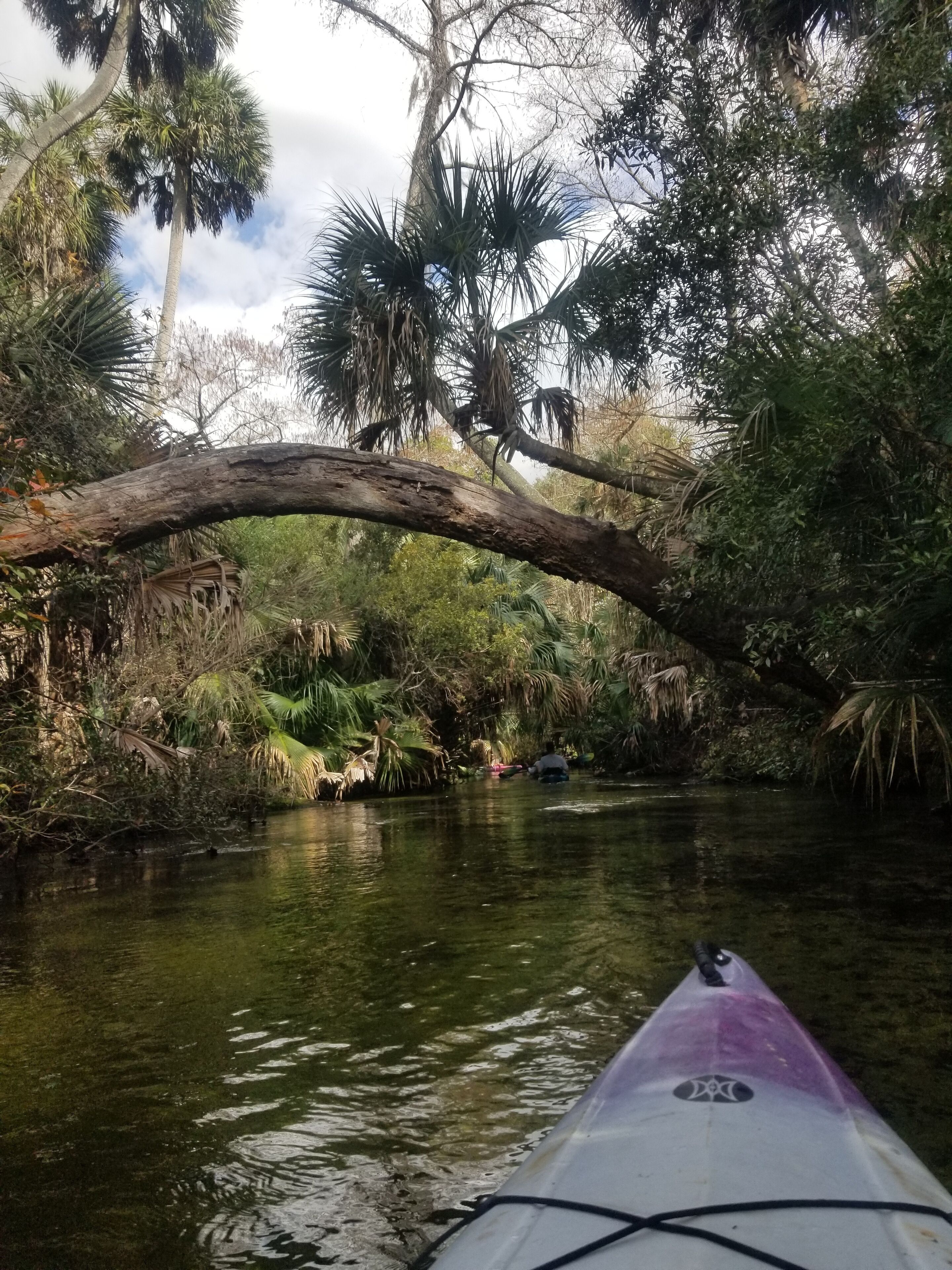 Un kayak su un fiume tranquillo, con un ponte naturale sopra.