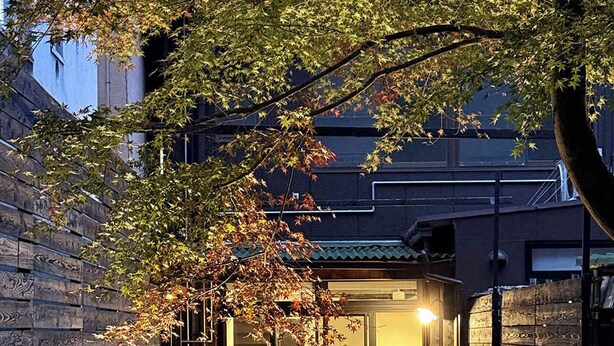 A modern building with a traditional Japanese-style entrance, a stone lantern, and a brick pathway leading to the entrance. - b hotel Kaniwasou | Miyajima Island Stay 11 (Hatsukaichi)