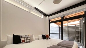 A modern hotel room with a large bed, a view of the sea through large windows, and a wooden ceiling. - b hotel Kaniwasou | Miyajima Island Stay 11 (Hatsukaichi)