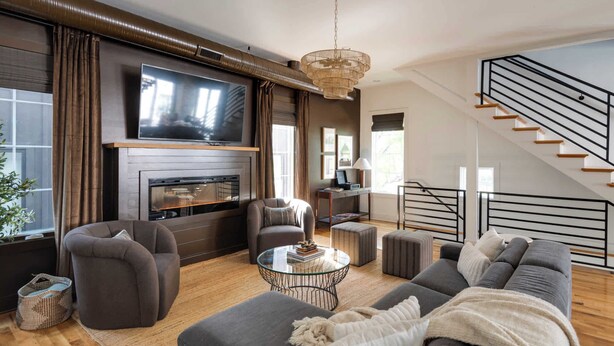 A modern living room with a fireplace, a large flat-screen TV, and a staircase. - The Gambler - Pool Table + Rooftop Lounge! (Nashville)