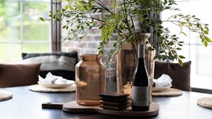 A dining table with a bottle of wine, a glass jar, and a potted plant. - The Gambler - Pool Table + Rooftop Lounge! (Nashville)