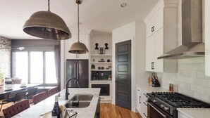 A modern kitchen with a central island, stainless steel appliances, and a large window providing natural light. - The Gambler - Pool Table + Rooftop Lounge! (Nashville)