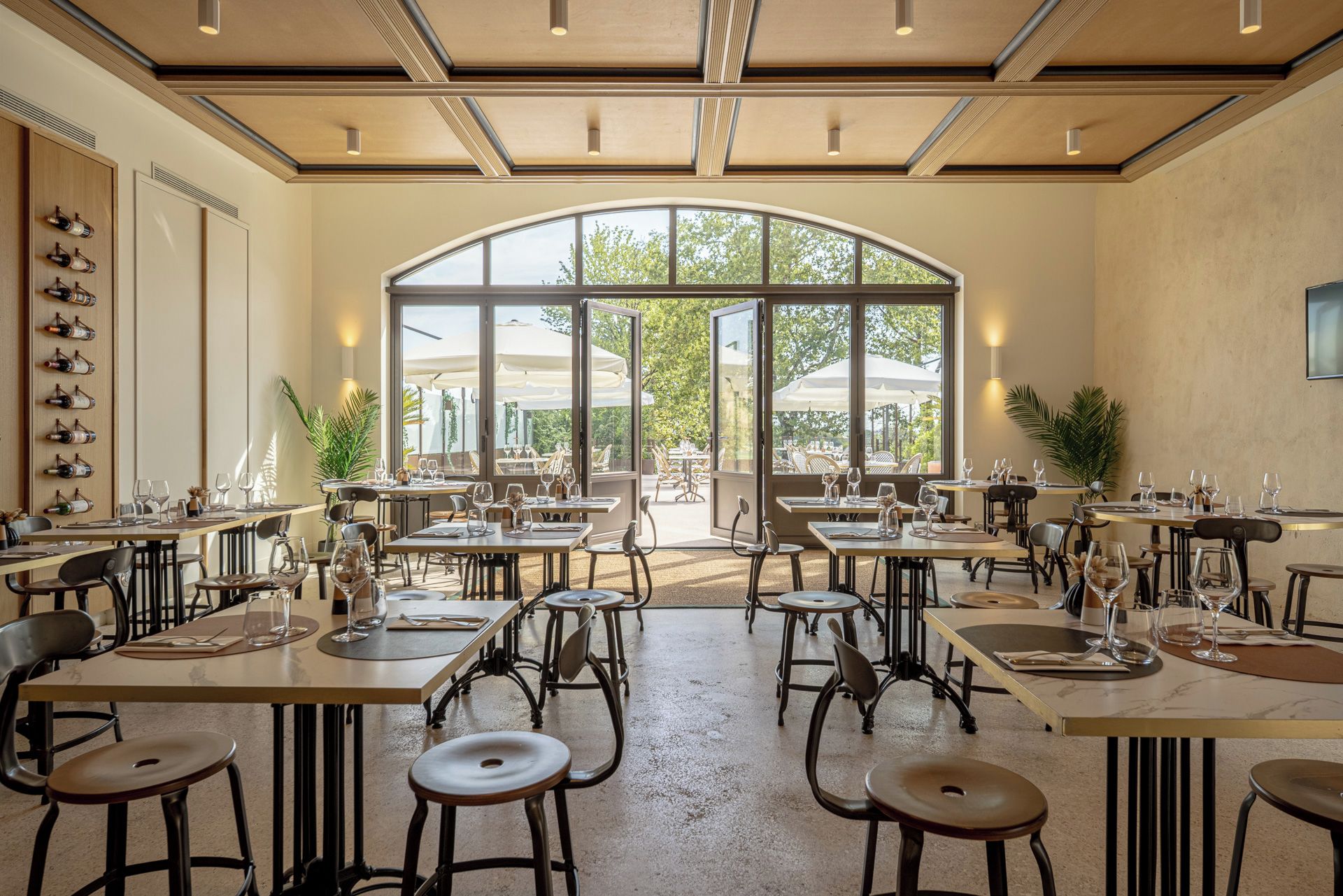 Un espace de restauration intérieur avec des tables et des chaises, de grandes fenêtres et une vue sur l’extérieur.