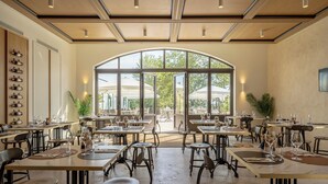 Un comedor interior con mesas y sillas, ventanas amplias y vistas al exterior.
