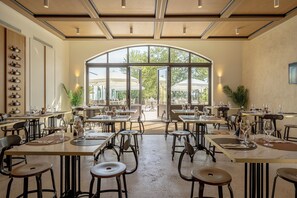 Un comedor interior con mesas y sillas, ventanas amplias y vistas al exterior.