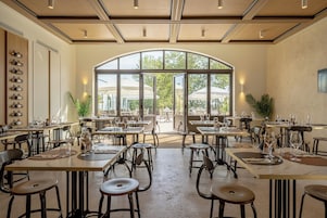 Un comedor interior con mesas y sillas, ventanas amplias y vistas al exterior.