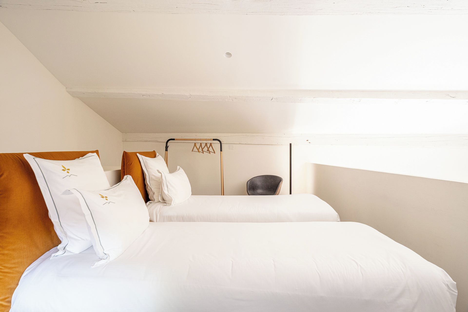 Une chambre avec deux lits, une chaise et un porte-vêtements suspendu.