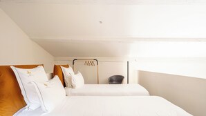 Un dormitorio con dos camas, una silla y un perchero.