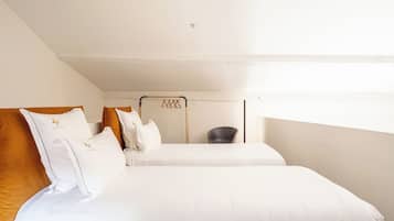 Une chambre avec deux lits, une chaise et un porte-vêtements suspendu.