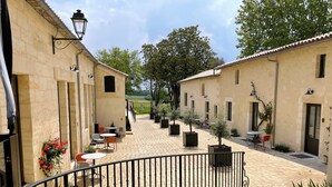 A courtyard with outdoor seating, potted plants, and a stone pathway. - Aux Ducs De Sienne (Montagne)
