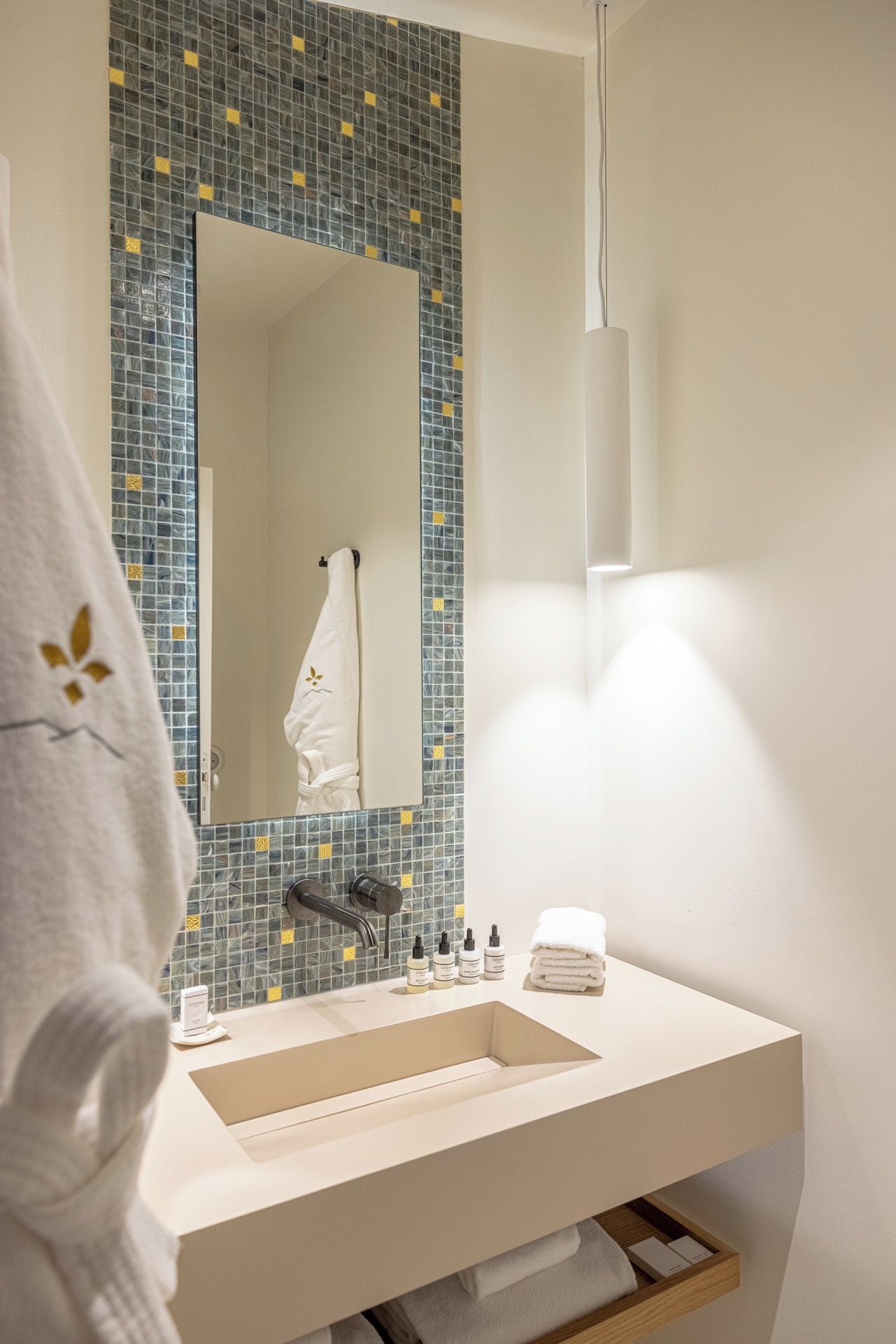 A bathroom with a sink, mirror, and towel rack.