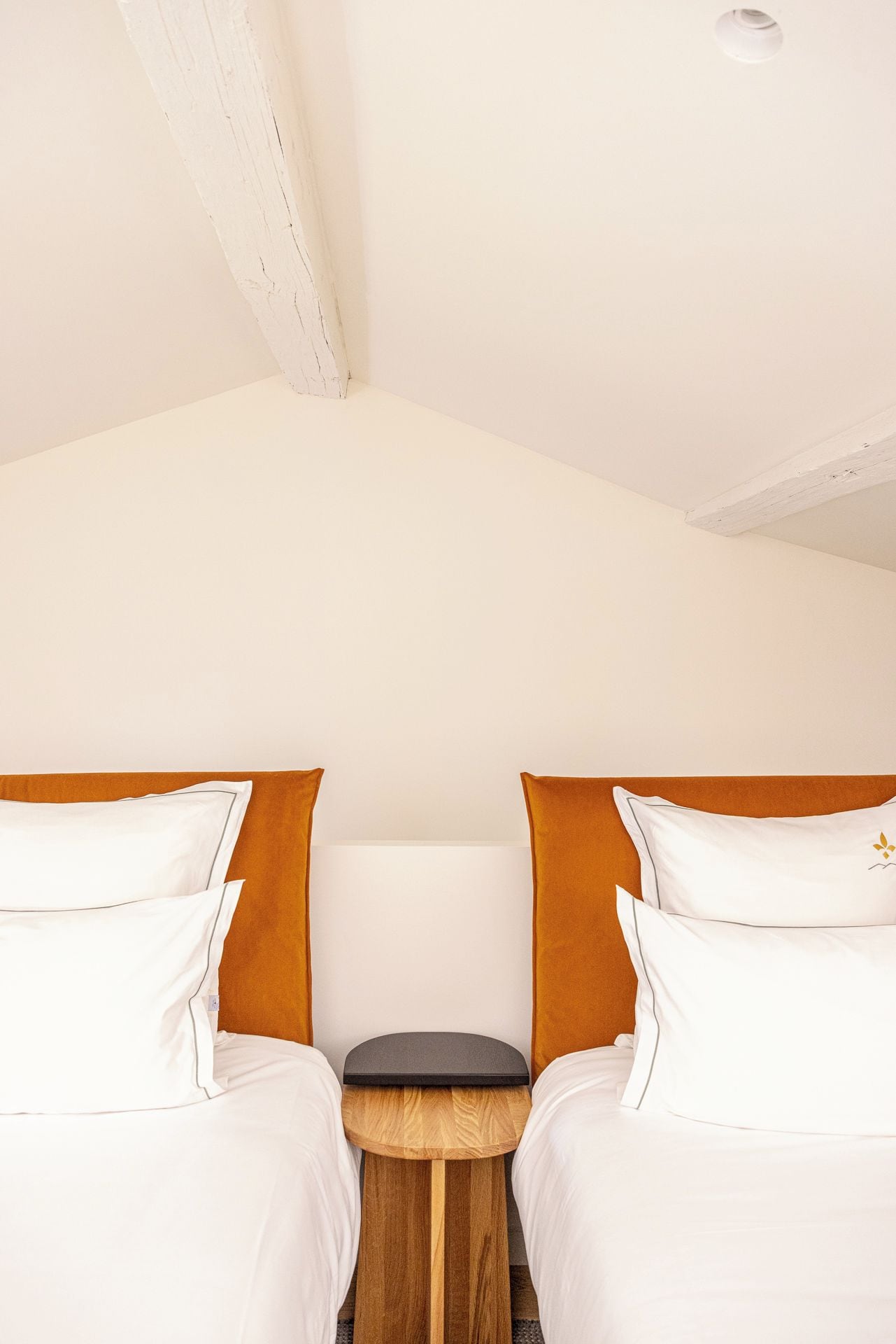Un dormitorio con dos camas, una mesita de noche de madera y un techo blanco.