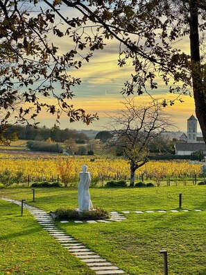 Una estatua en un parque, con un viñedo e iglesia al fondo.