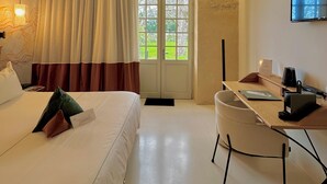 A hotel room with a bed, a desk, a chair, a TV, and a window with curtains. - Aux Ducs De Sienne (Montagne)