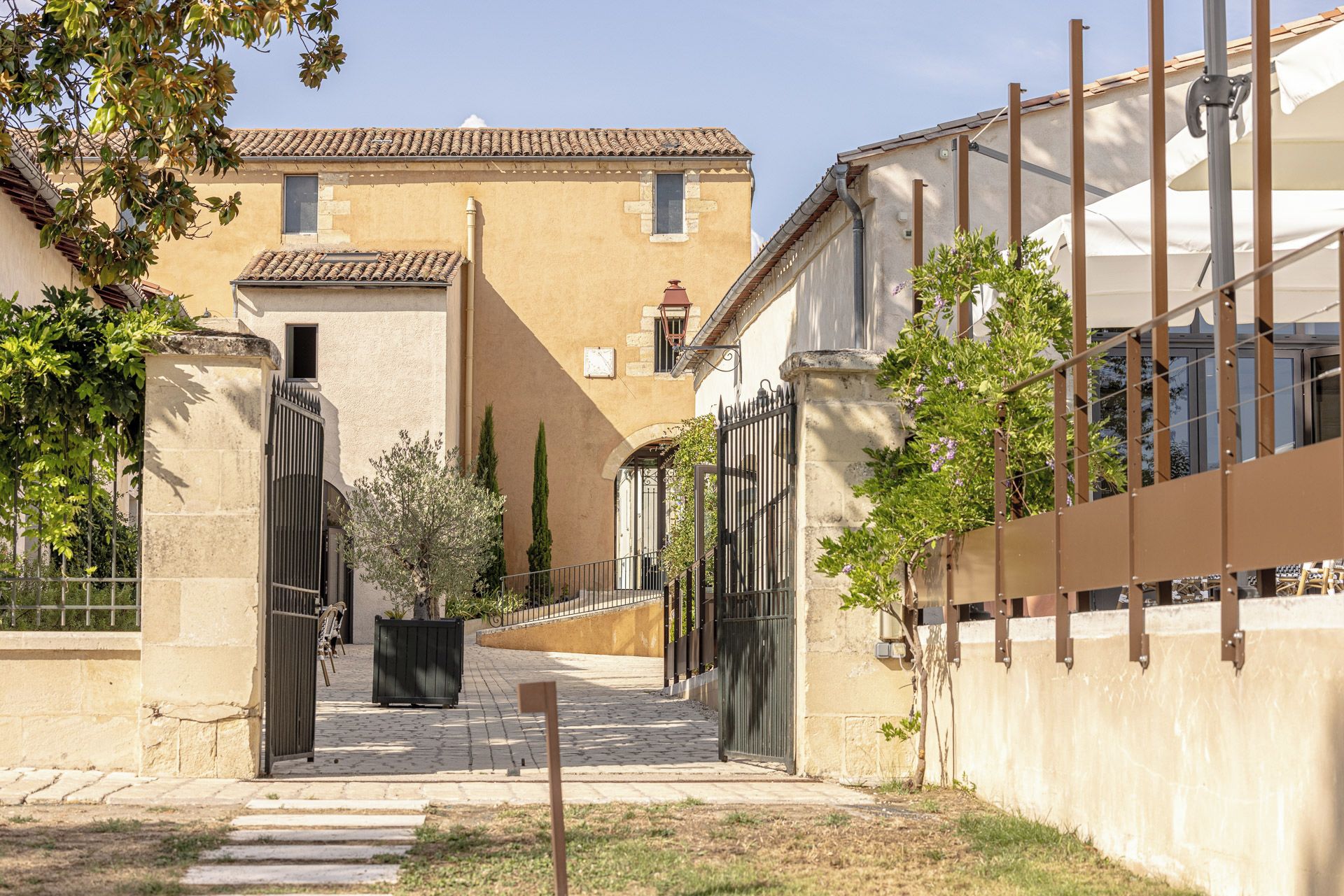 A courtyard with a paved walkway, a gate, and a building with a tiled roof.