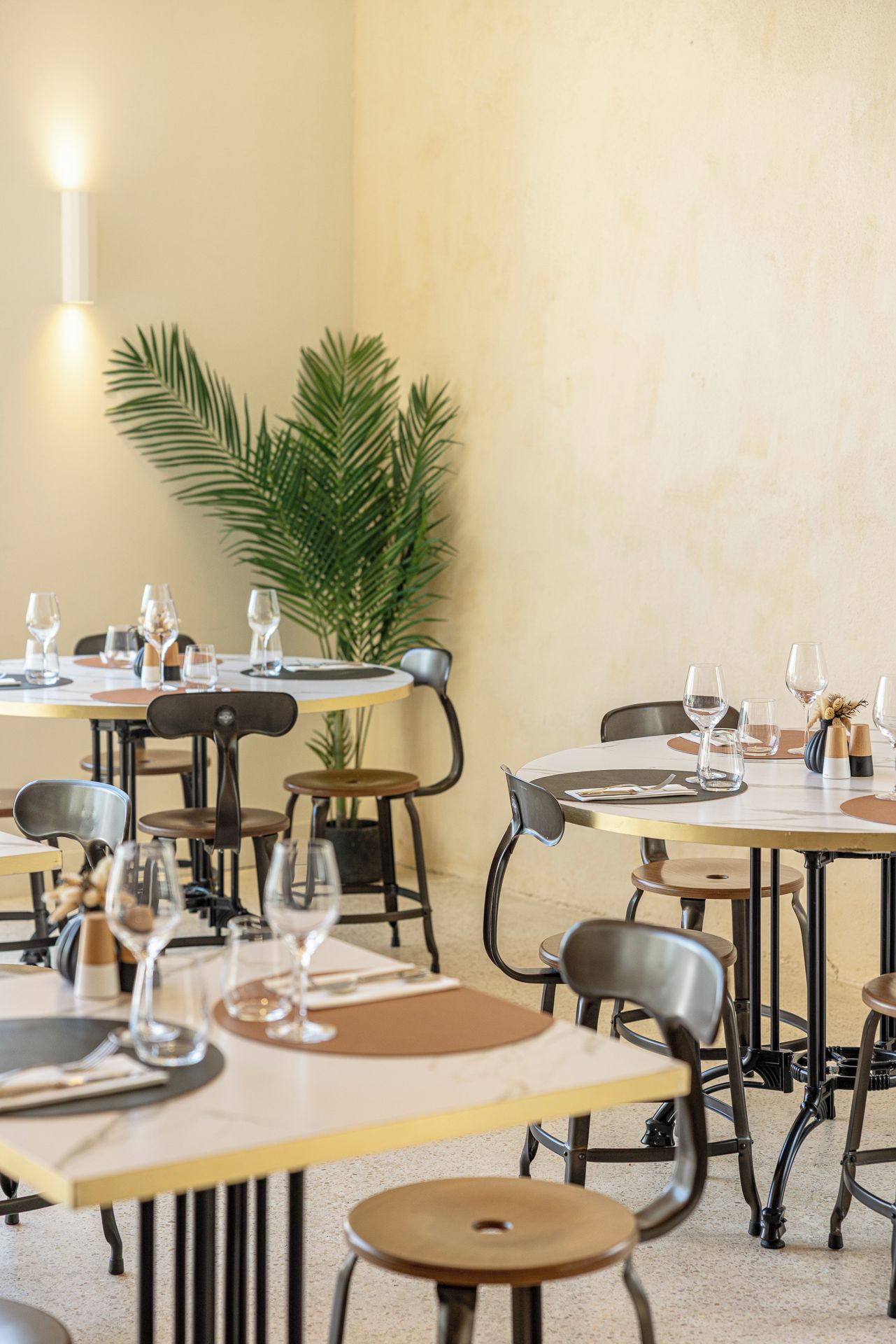 Un restaurant avec des tables rondes, des chaises et des verres à vin vides.