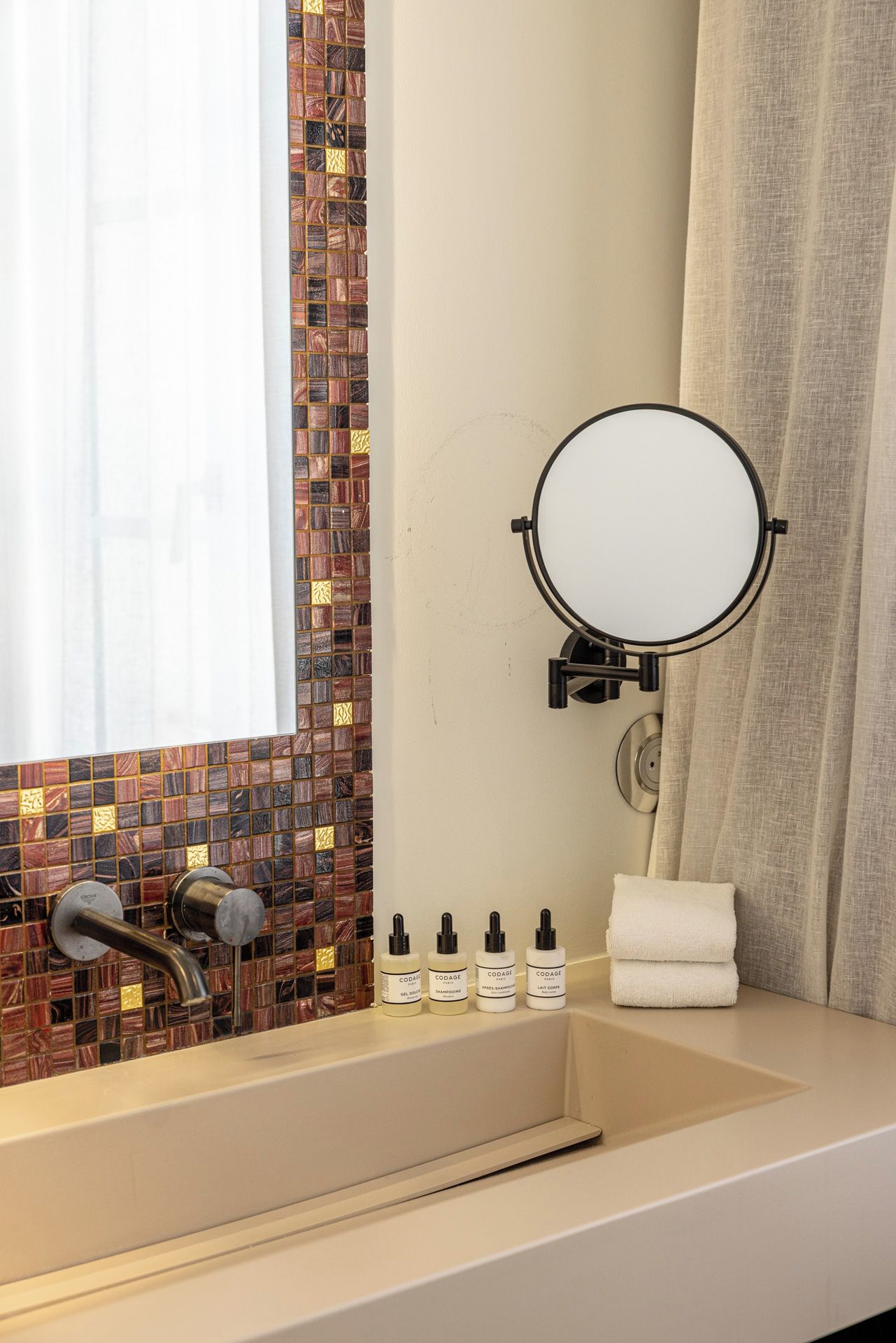 Un baño con lavamanos, espejo y artículos de aseo.