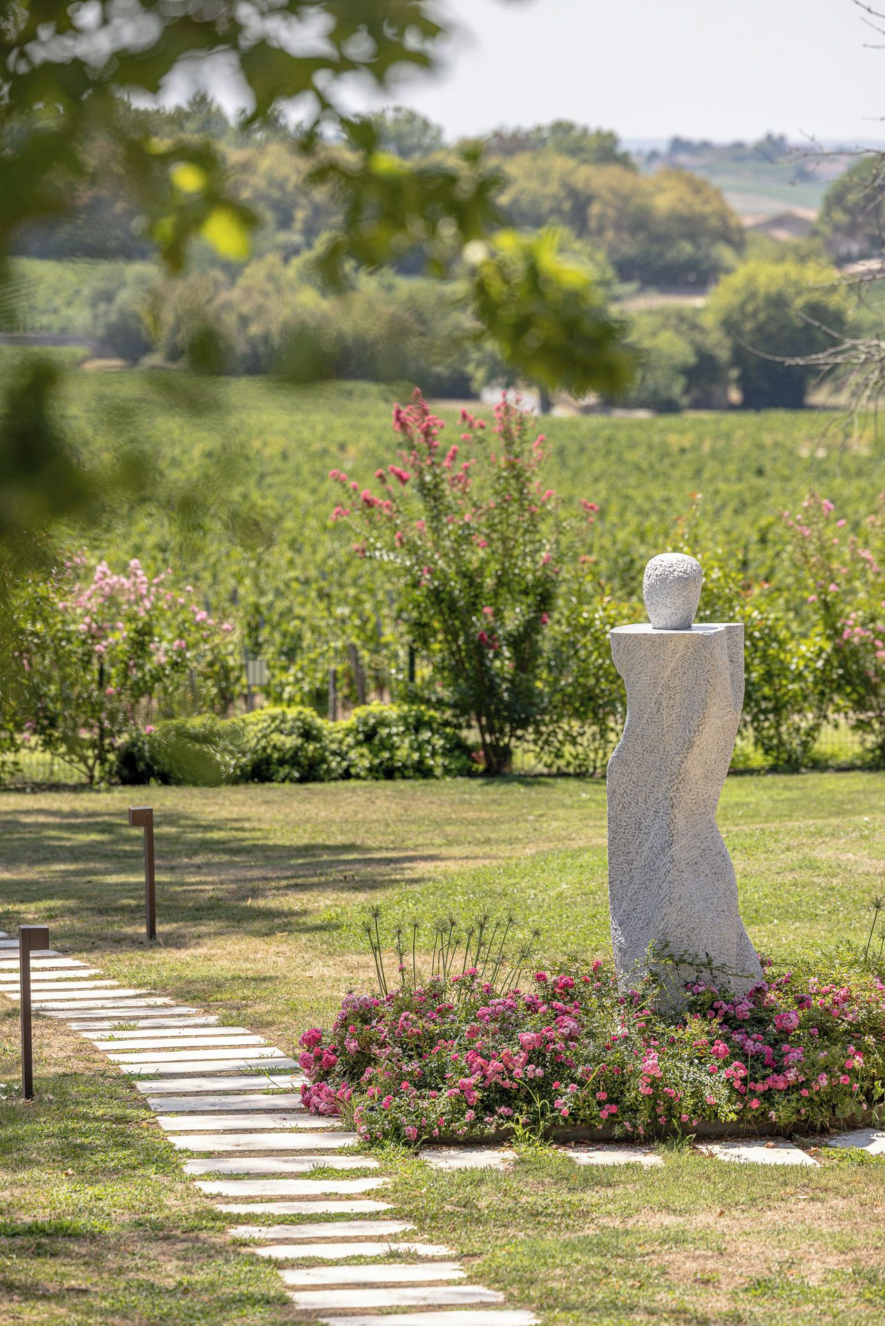 A garden with a unique sculpture, a pathway, and flowering plants.