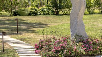 A garden with a unique sculpture, a pathway, and flowering plants.