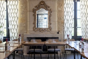 Un comedor con chimenea, un espejo grande y decorativo, y cortinas estampadas.