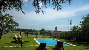 Zona de piscina con sillas de descanso, vista despejada hacia un edificio distante y un farol.