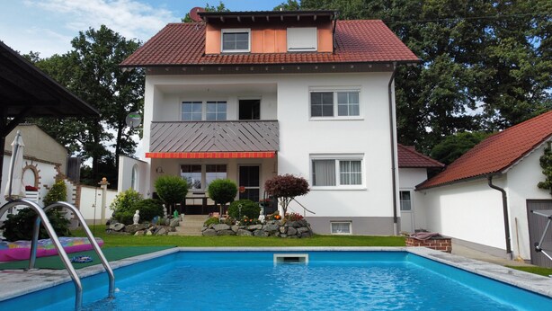 Ein zweistöckiges Haus mit einem Schwimmbecken davor.