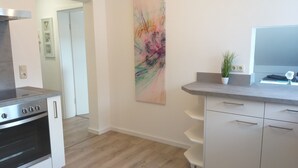 Eine moderne Küche mit Backofen, einer Arbeitsplatte mit Topfpflanze und einem großen abstrakten Gemälde an der Wand.