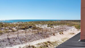 Vistes a la platja amb una tanca de fusta i unes escales que baixen cap a la sorra.