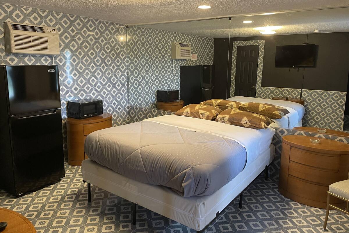 A hotel room with a bed, a TV, a microwave, a refrigerator, and patterned walls.
