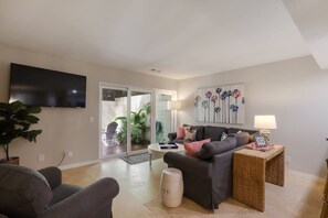 A living room with a sofa, a coffee table, a TV, and a sliding glass door leading to a patio.